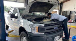 white truck with the hood open and a technician is inspecting