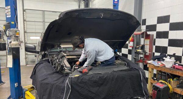 technician working in the hood of a car